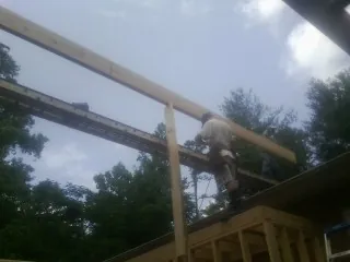 Carpenter setting a ridge beam over a new addition frame — Ice Dam Removal by Roofing Brothers in Drakesboro