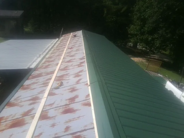 Old rusted panels beside newly installed green metal roofing — Wind Damage Roof Repair by Roofing Brothers in Drakesboro