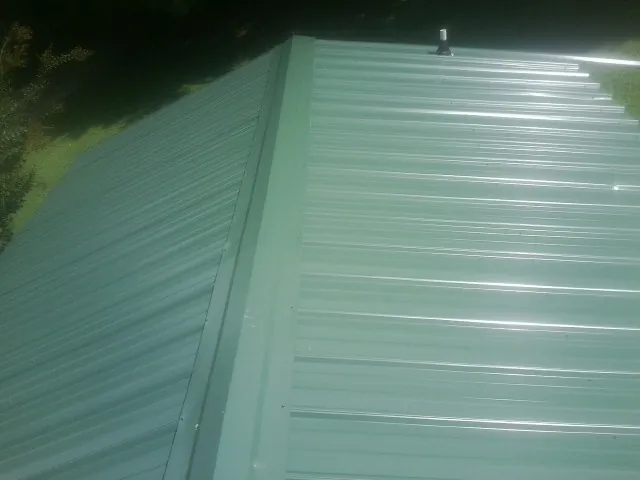 New green metal panels meeting at the ridge of a roof — Flat Roof Repair work by our crew in Drakesboro