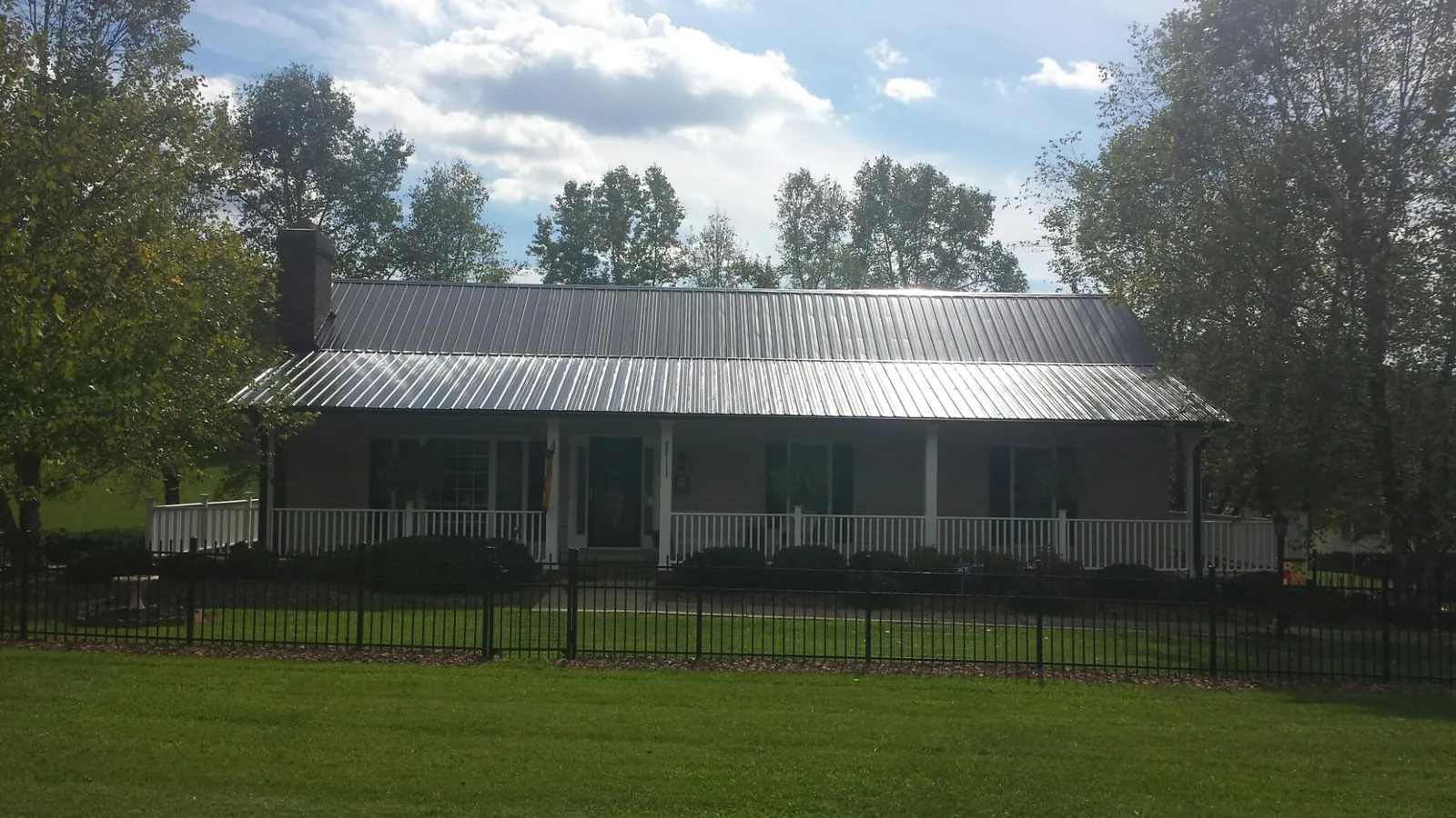 Gray metal roof on a brick ranch with a full width front porch — Gutter Guard Installation work by our crew in Drakesboro