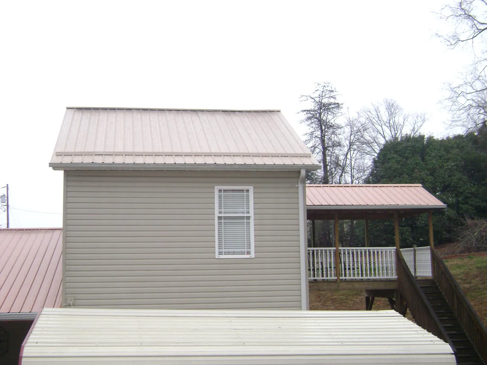 Tan metal roofs on a two story addition and attached porch, from a Roof Replacement job in Drakesboro