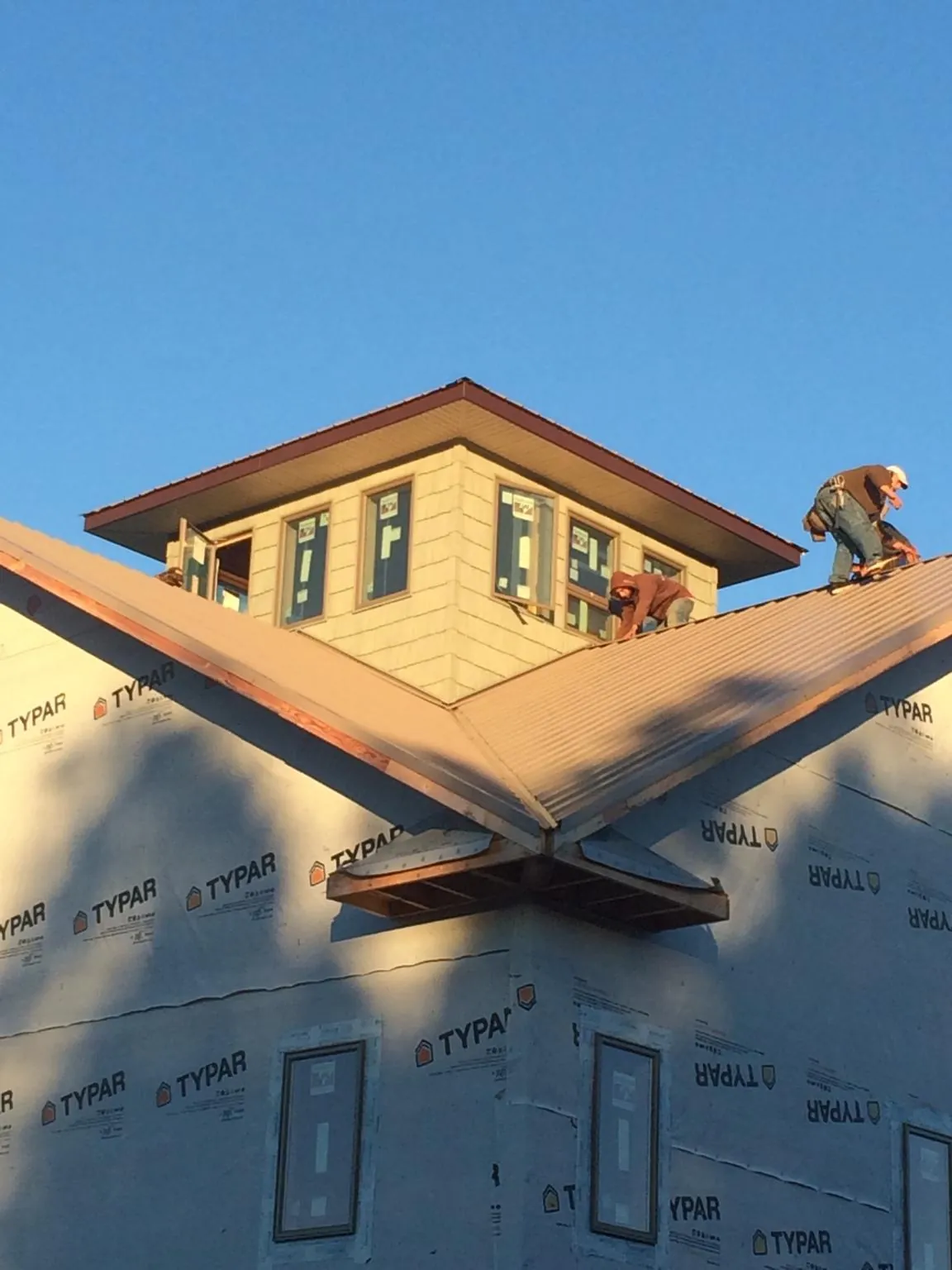 Roofers working around a rooftop cupola on a new metal roof at sunset — Roof Waterproofing in Drakesboro by Roofing Brothers